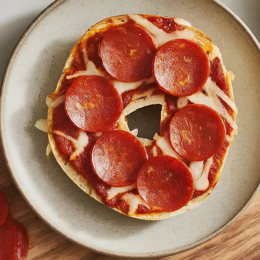 A colorful plate of mini pizza bagels topped with cheese, pepperoni, and veggies, perfect for kids' snacks or meals.