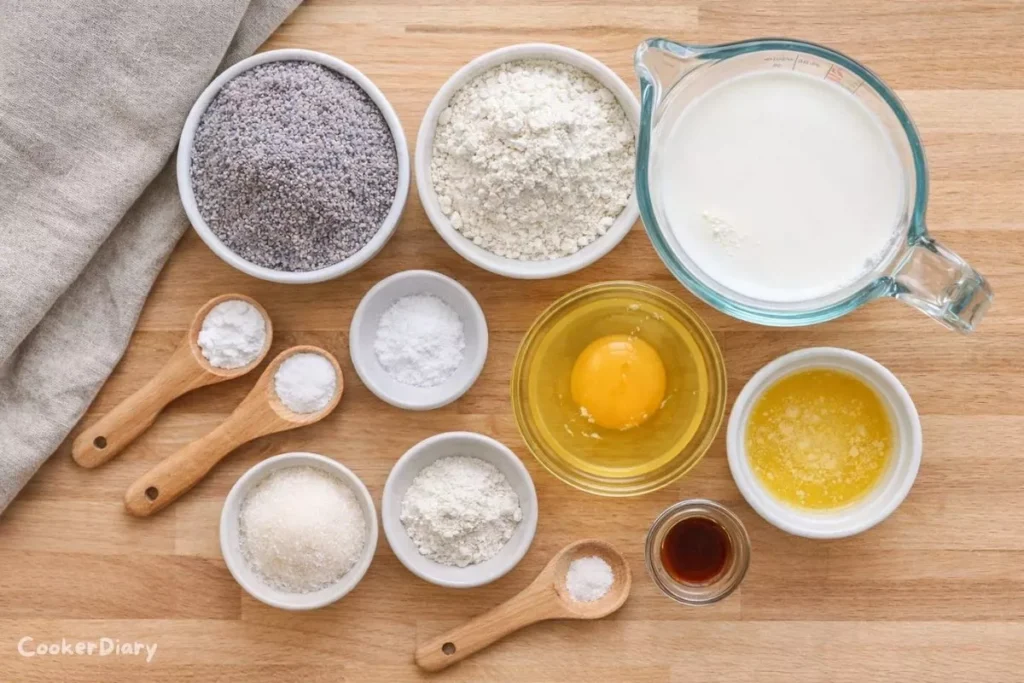 Flat-lay of raw ingredients for blue corn pancakes including cornmeal, gluten-free flour, milk, egg, butter, and spices.