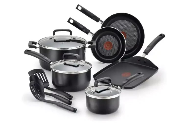 A set of nonstick T-fal cookware, including frying pans, saucepans, and a stockpot with glass lids, arranged neatly on a kitchen counter.