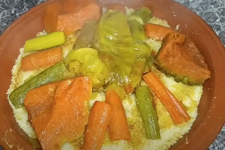 Moroccan couscous with colorful vegetables like carrots, zucchini, and bell peppers, garnished with herbs.