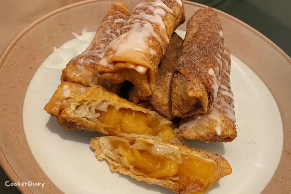 Golden crispy peach cobbler egg rolls served with a side of vanilla ice cream on a white plate