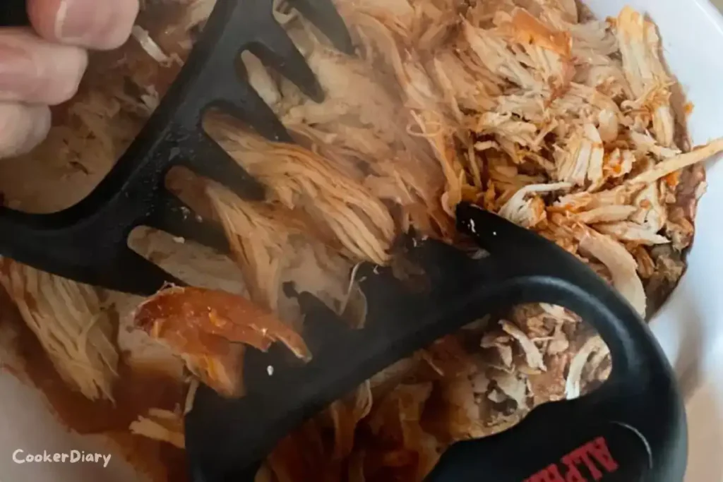 Alpha Grillers meat shredder claws with ergonomic handles on a wooden cutting board with shredded pulled pork