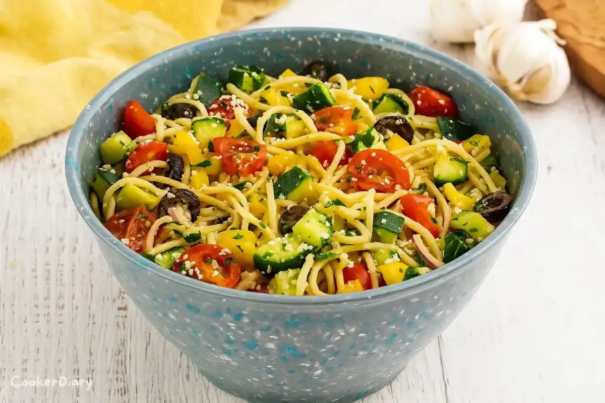 Colorful spaghetti salad with vegetables and dressing served in a gray bowl