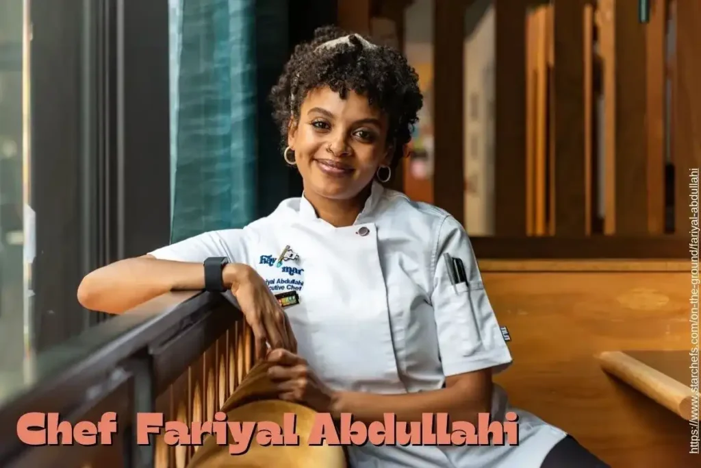 Chef Fariyal Abdullahi confidently standing on a sofa, smiling and dressed in casual chic attire