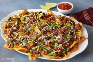 Monster nachos served on a white platter with melted cheese, toppings, and garnishes