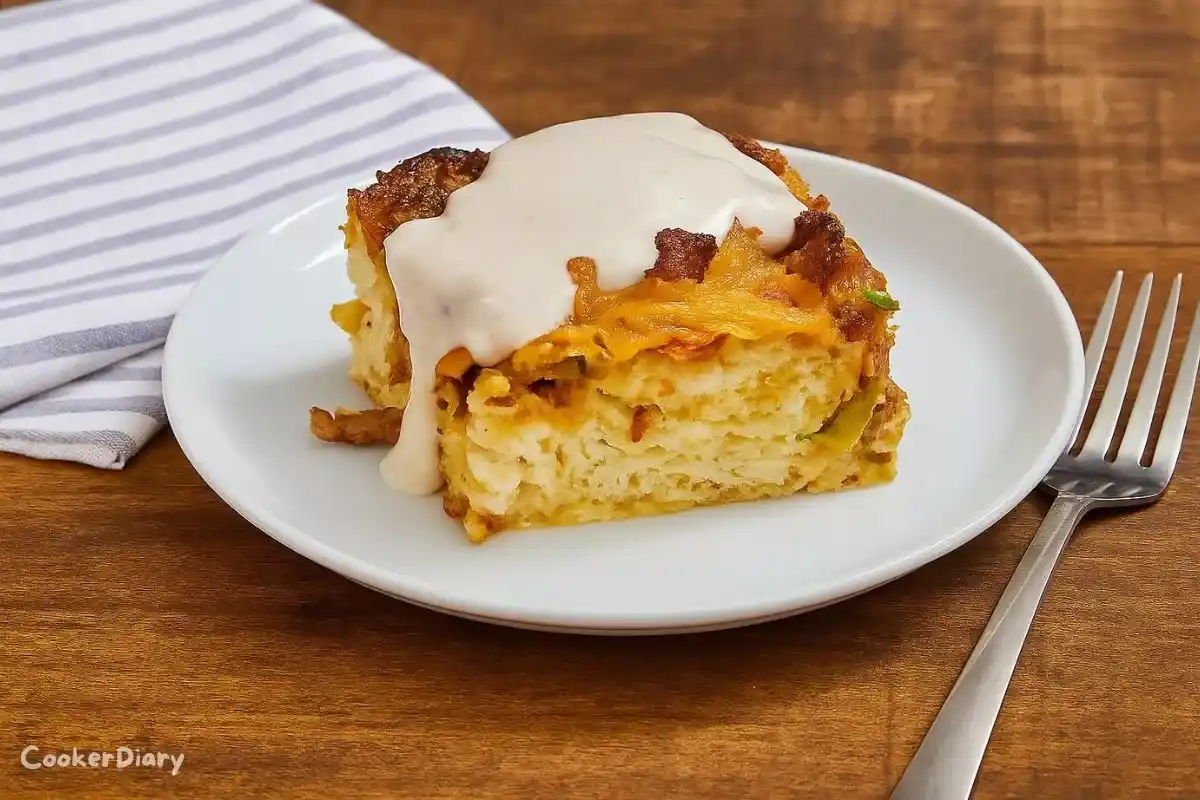 Angled close-up of baked sausage biscuit slice with a square being lifted.